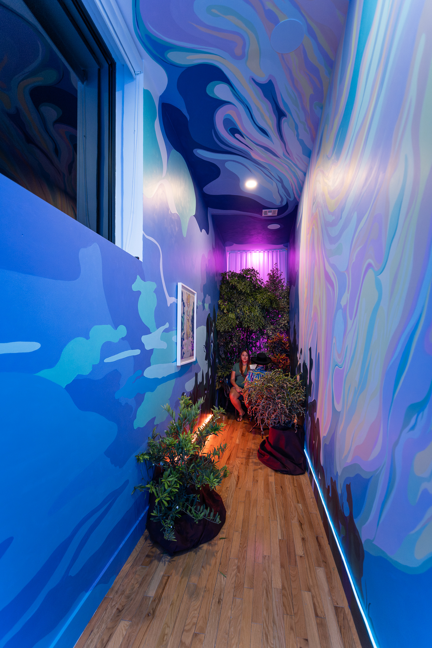 Visitors walking through the immersive hallway mural, surrounded floor-to-ceiling by saturated painted color
